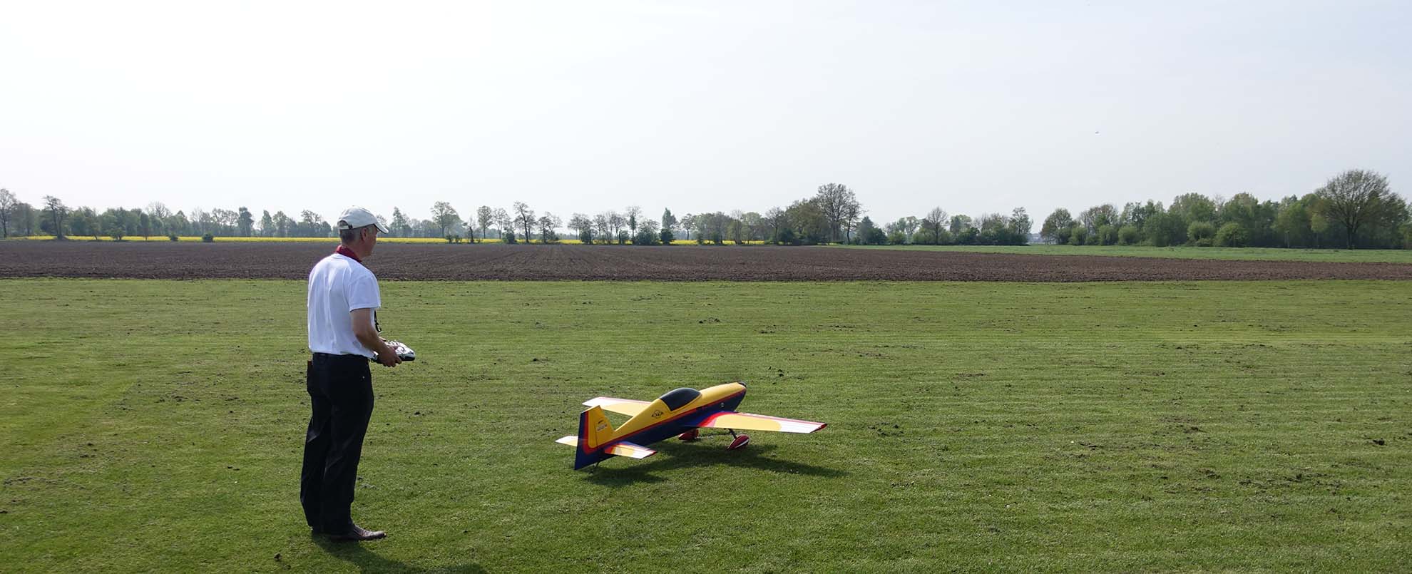 Ein Mann auf einer Wiese startet ein ferngesteuertes Flugzeug